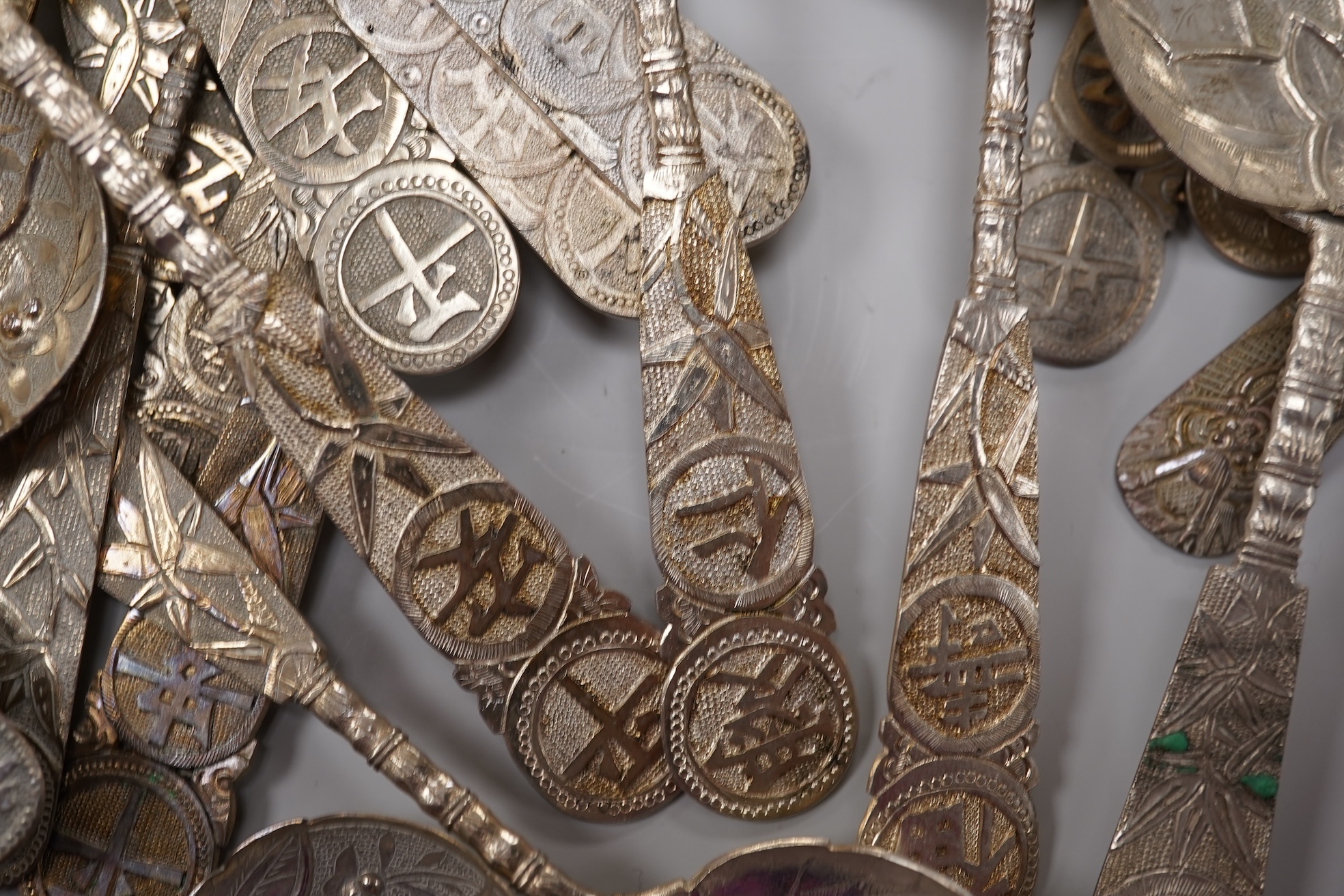 A set of twelve early 20th century Chinese Export white metal small spoons, maker LS, decorated with foliage and character mark, 10cm, a set of ten similar larger spoons, same maker, 12.3cm and another set a six similar